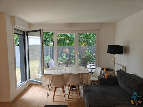 een woonkamer met een tafel en een bank bij l'Éden familial - cosy T3 proche Disneyland avec jardin in Vaires-sur-Marne