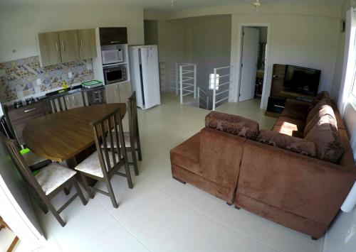 sala de estar con sofá, mesa y cocina en Costa do Sol Residencial, en Bombinhas