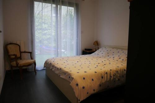 ein Schlafzimmer mit einem Bett, einem Stuhl und einem Fenster in der Unterkunft Maison moderne proche de Paris in Montigny-lès-Cormeilles