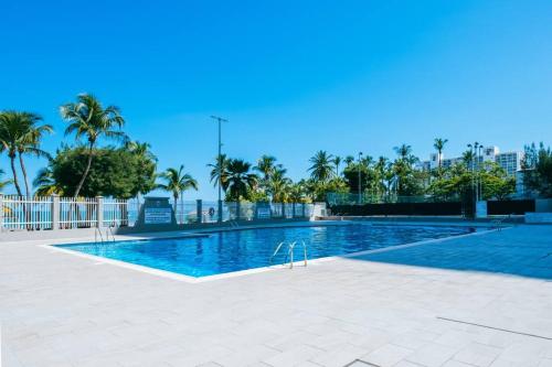 een groot zwembad met palmbomen op de achtergrond bij Buena Vida Beach Studio Puerto Rico in San Juan