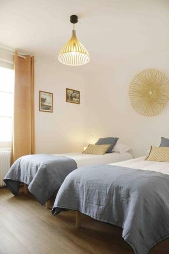 une chambre avec deux lits et un lustre dans l'établissement Paddock Prestige by La Boîte En Plus, à Chantilly