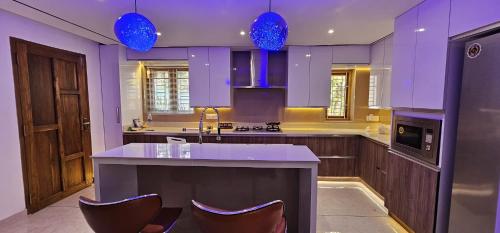 a kitchen with purple cabinets and a counter with chairs at Thekkumbath Sea Breeze Pool villa in Kannur