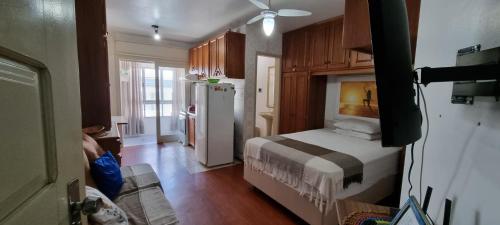 a small room with a bed and a refrigerator at Apartamento em Tramandaí in Tramandaí