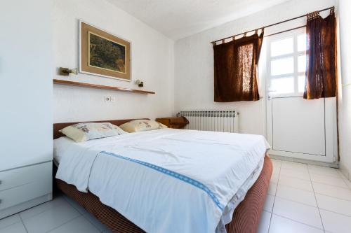 een slaapkamer met een bed met witte lakens en een raam bij Apartment Slavko R in Supetarska Draga