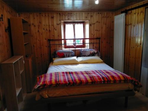 Cama en habitación de madera con ventana en Casa dei sogni, en Aosta