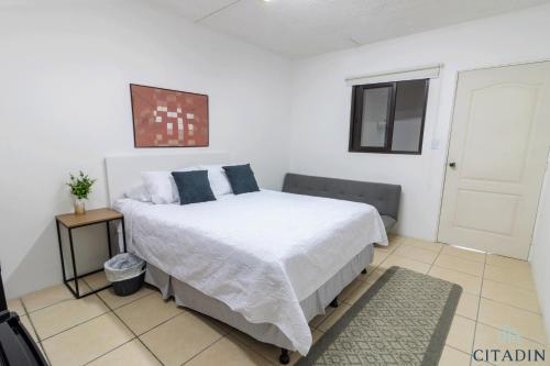 a bedroom with a bed with white sheets and a window at Hotel Citadin Zona 4 in Guatemala