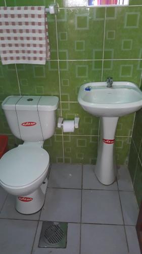 uma casa de banho com azulejos verdes, um WC e um lavatório. em Hostal Arco Iris del Lago em Copacabana