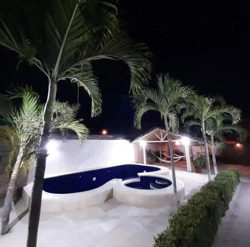 un patio con palmeras y una piscina por la noche en Casa con piscina y salida a la playa en Playas