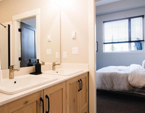 a bathroom with two sinks and a bed at New! Luxury, Top Floor, Ski in/Ski Out, Private Hot Tub and Mountain Views in Sun Peaks