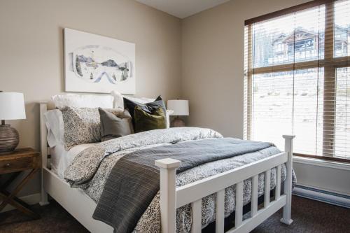 a bedroom with a white bed and a window at New! Luxury, Top Floor, Ski in/Ski Out, Private Hot Tub and Mountain Views in Sun Peaks
