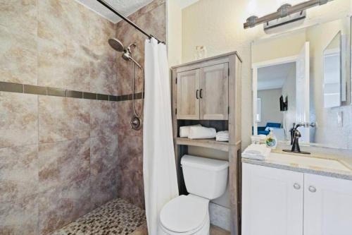 uma casa de banho com um WC, um chuveiro e um lavatório. em Paradise Found Luxurious Retreat with Heated Pool em Rockledge