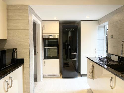 Il comprend une cuisine équipée d'un réfrigérateur noir et blanc. dans l'établissement Luxury 4 Bedroom Holiday Home, à Baguley