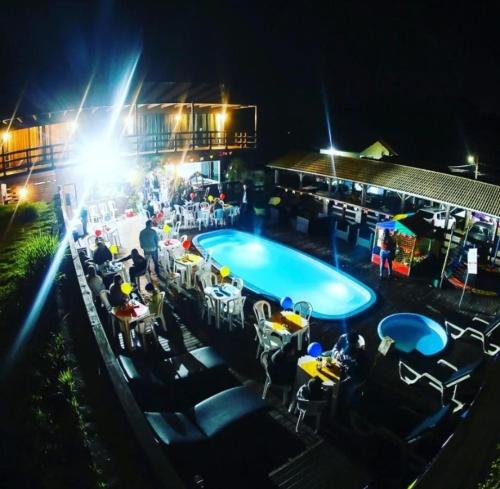 a swimming pool at night with people sitting around it at Suite Farol do Arvoredo in Governador Celso Ramos
