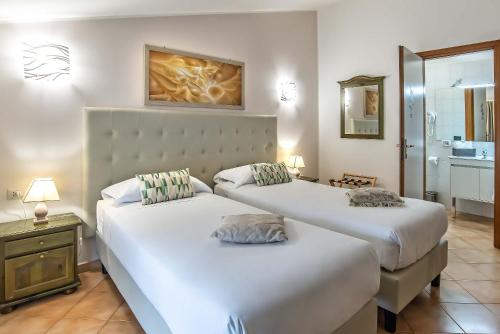 two beds in a hotel room with a bathroom at Plaza Rooms Ciampino in Ciampino