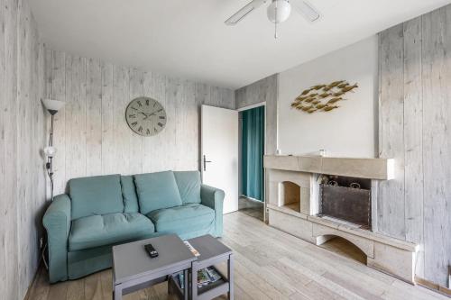 un salon avec un canapé bleu et une cheminée dans l'établissement Appartement Paroco - Welkeys, à Cabourg
