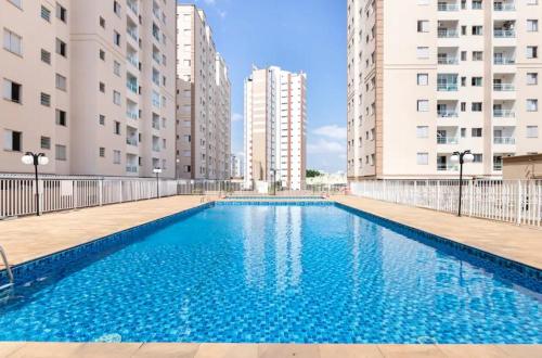 a swimming pool in the middle of two buildings at Apto 3Q Suíte Shopping Taubaté in Taubaté