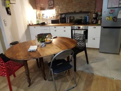 una cucina con tavolo e sedie in legno e frigorifero di Prodhomme Olivier a Betton