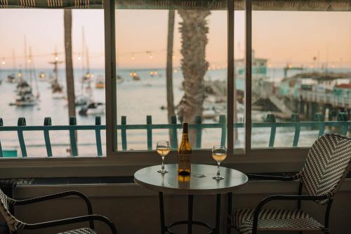 a table with two glasses of wine and a view of a harbor at The Edgewater in Avalon