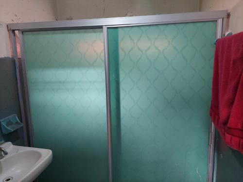 - szklane drzwi do prysznica w łazience z umywalką w obiekcie Habitación muy amplia céntrica cerca de avenidas principales w mieście Aguascalientes