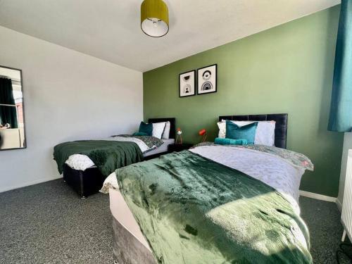 twee bedden in een kamer met groene muren bij Canvey Island Bliss By Artisan Stays I Free Parking I Weekly & Monthly Stay Offer in Canvey Island