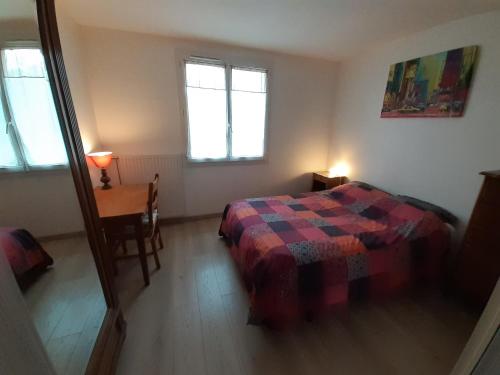 Maison 3 chambres avec jardinet في Ris-Orangis: غرفة نوم بسرير وطاولة ونوافذ