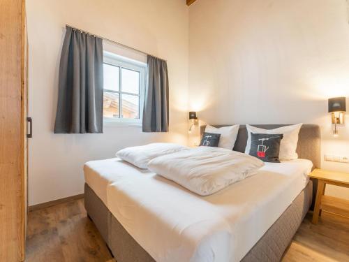 a bedroom with a large white bed with a window at Chalet Aquila in Niedernsill