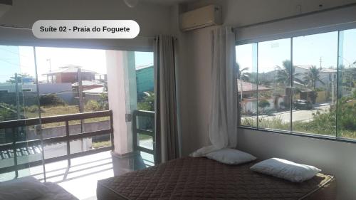 a bedroom with a bed and a large window at Praia do Foguete - Aluguel Econômico in Cabo Frio