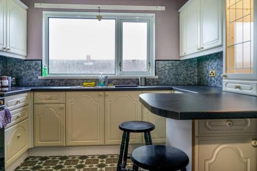 a kitchen with a counter and two stools in it at 2 Bed Apartment near Belfast & Ferry in Belfast