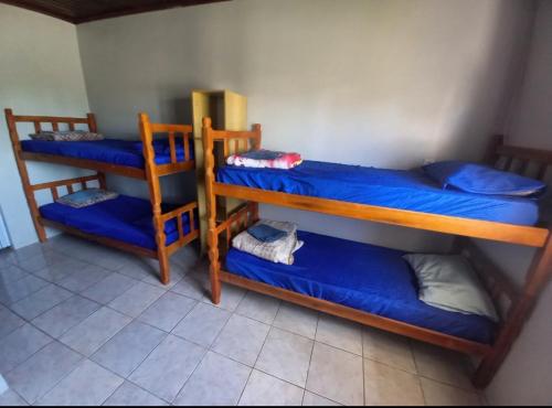 a room with three bunk beds with blue sheets at Hosthê compartilhados in Canoas