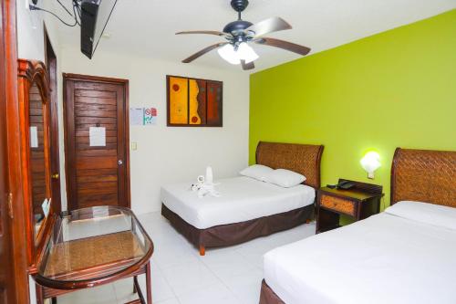 een hotelkamer met 2 bedden en een plafondventilator bij Hotel Parador in Cancun