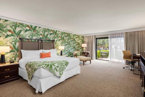 a bedroom with a large white bed and a desk at Tommy Bahama Miramonte Resort & Spa in Indian Wells