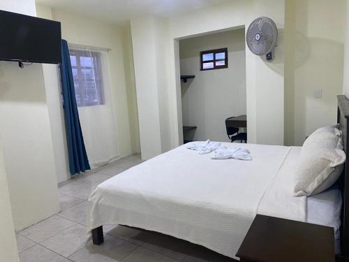Hotel Magnolia Tek Ulte´ في كوميتان د دومينغوز: غرفة نوم بسرير ابيض وساعة على الحائط