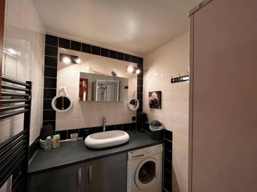 a bathroom with a sink and a washing machine at Appartement avec Terrasse & Piscine Privée, Gérardmer - FR-1-589-56 in Gérardmer