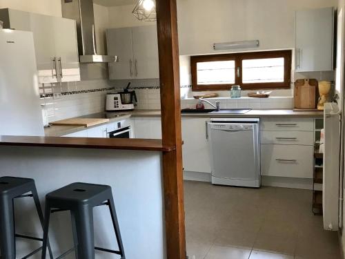 - une cuisine avec des appareils électroménagers blancs et 2 tabourets dans l'établissement Gîte charmant près du circuit du Mans, 12 pers., 5 ch., rénové avec 3 sdb, nature et attractions proches - FR-1-410-342, à Yvré-lʼÉvêque