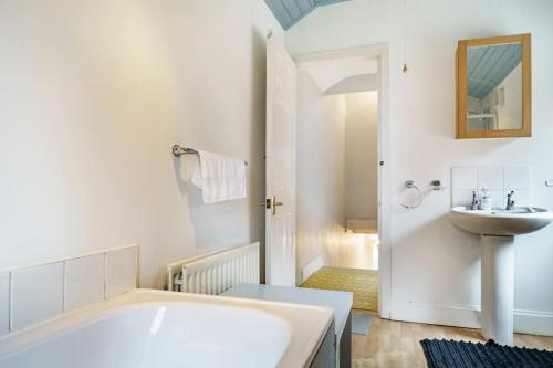 a bathroom with a white tub and a sink at House Close to City Centre and City Airport in Belfast