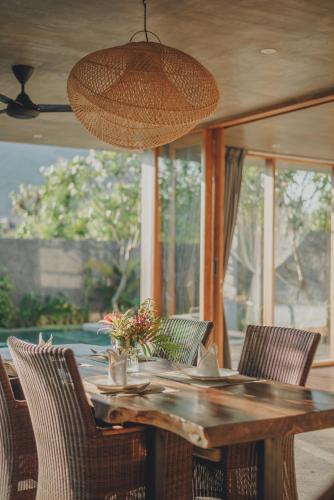 a wooden table with chairs and a light fixture at Villa Danginan & Dajanan Pemuteran in Pemuteran