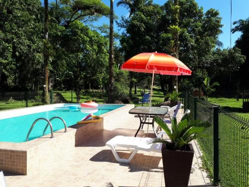 a patio with a table and an umbrella next to a pool at Chacara Salmo 27 in Antonina
