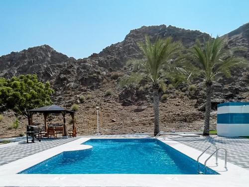 a swimming pool with palm trees and a mountain at Moon mountain villa 