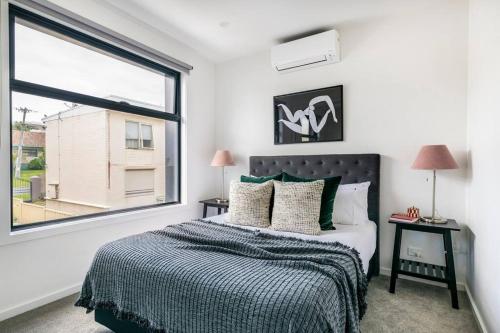 a bedroom with a bed and a large window at 3 BedroomTownhouse-free parking in Melbourne