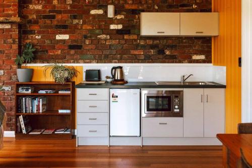 a kitchen with white appliances and a brick wall at The most beautiful guest retreat in Scamander