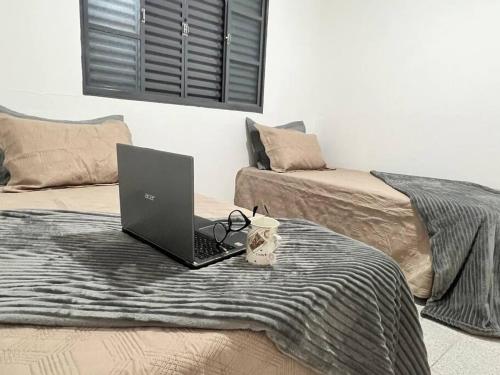 a laptop computer sitting on top of a bed at Acolhedora casa de 03 quartos in Passos
