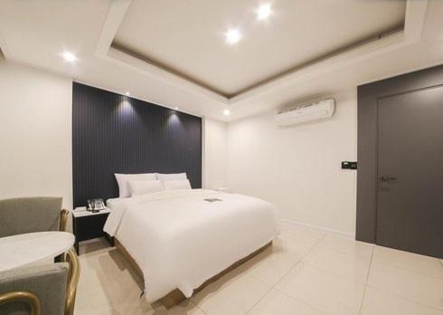 a bedroom with a white bed and a table at Rium Hotel in Mokpo
