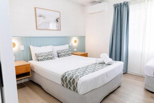 a bedroom with a large white bed and a window at Palm View Holiday Apartments in Bowen