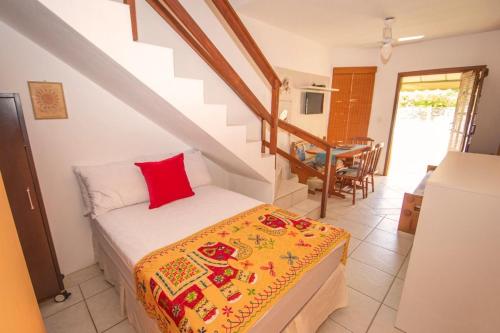 1 dormitorio con cama con almohada roja y escalera en Apartamentos Villa Porto do Sol, en Bombinhas