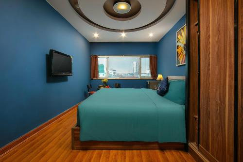 a blue bedroom with a bed and a tv at Hai Mươi Hotel & Apartment in Hanoi