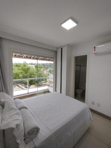 a bedroom with a large bed and a large window at Village Praia Dourada - Praia dos Milionários in Ilhéus