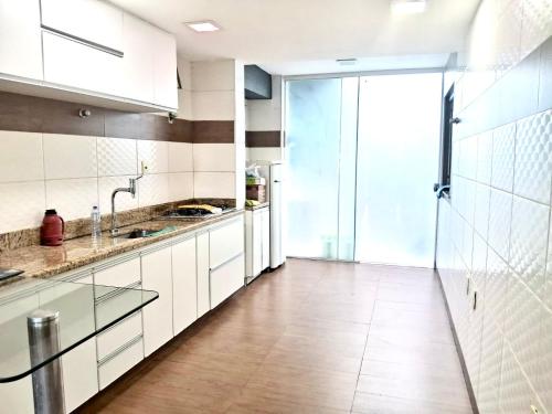 a kitchen with white cabinets and a large glass door at Excelente casa a 3km do centro de Itabira in Itabira