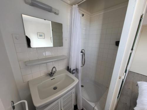 une salle de bain blanche avec un lavabo et une douche dans l'établissement Appartement T2 rénové face mer avec balcon, à 150m de la plage et 300m des commerces - FR-1-92-611, à Les Sables-dʼOlonne