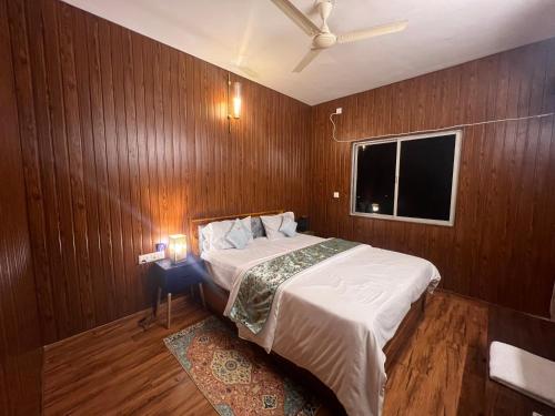 een slaapkamer met een bed met houten wanden en een raam bij Metro Nook in Lucknow