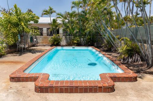 uma piscina com uma parede de tijolos à volta em Palm View Holiday Apartments em Bowen